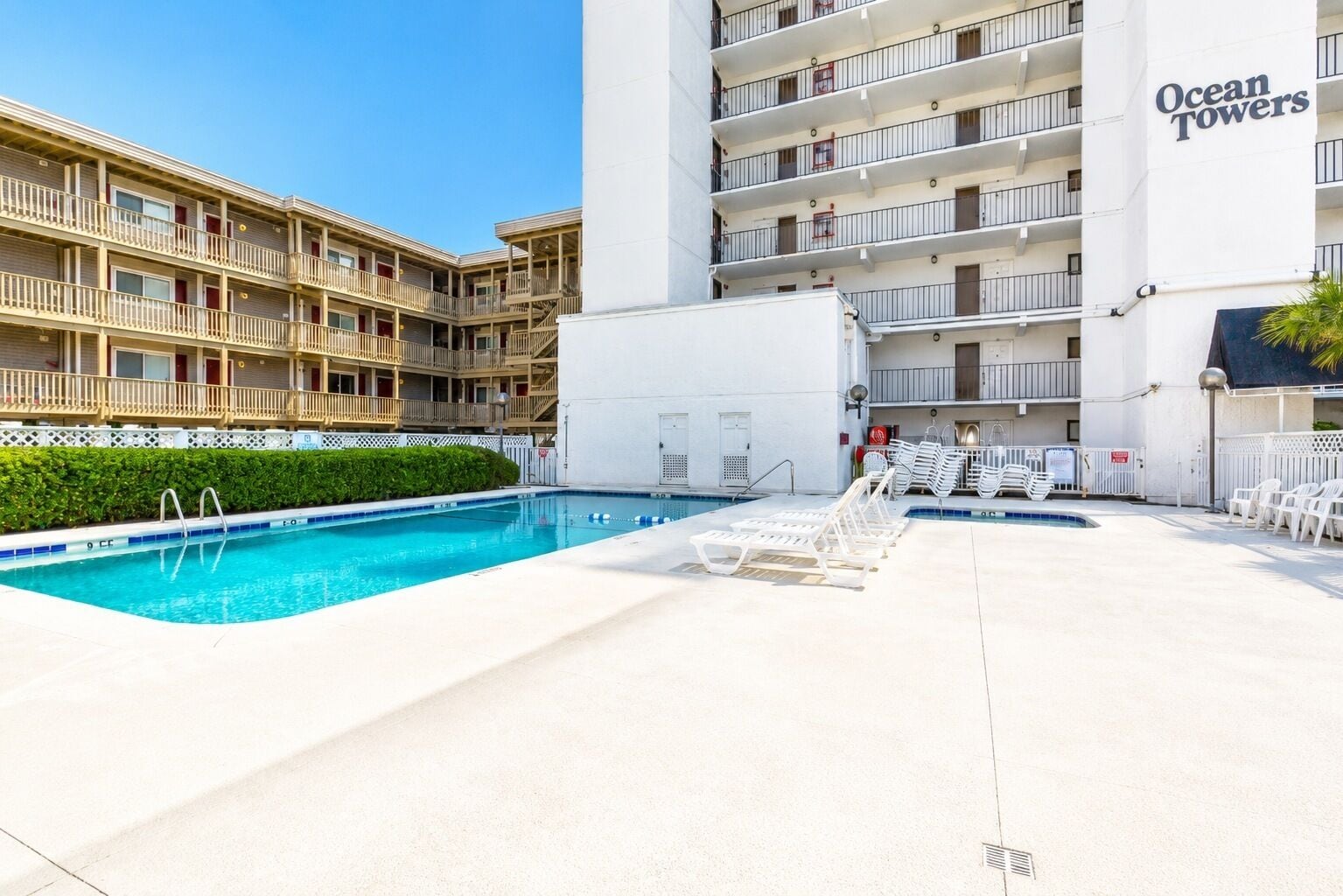Hotel amb piscina, gandules i edifici amb balcons.