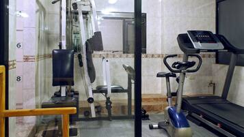 Uma academia com equipamentos de exercícios, esteira e um espelho.