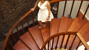 Uma escadaria em espiral com degraus de madeira e corrimão, que dá acesso a um andar superior.