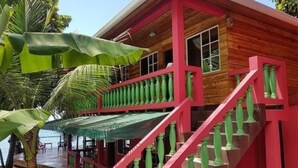 Una casa de madera con una escalera roja y un porche cubierto.