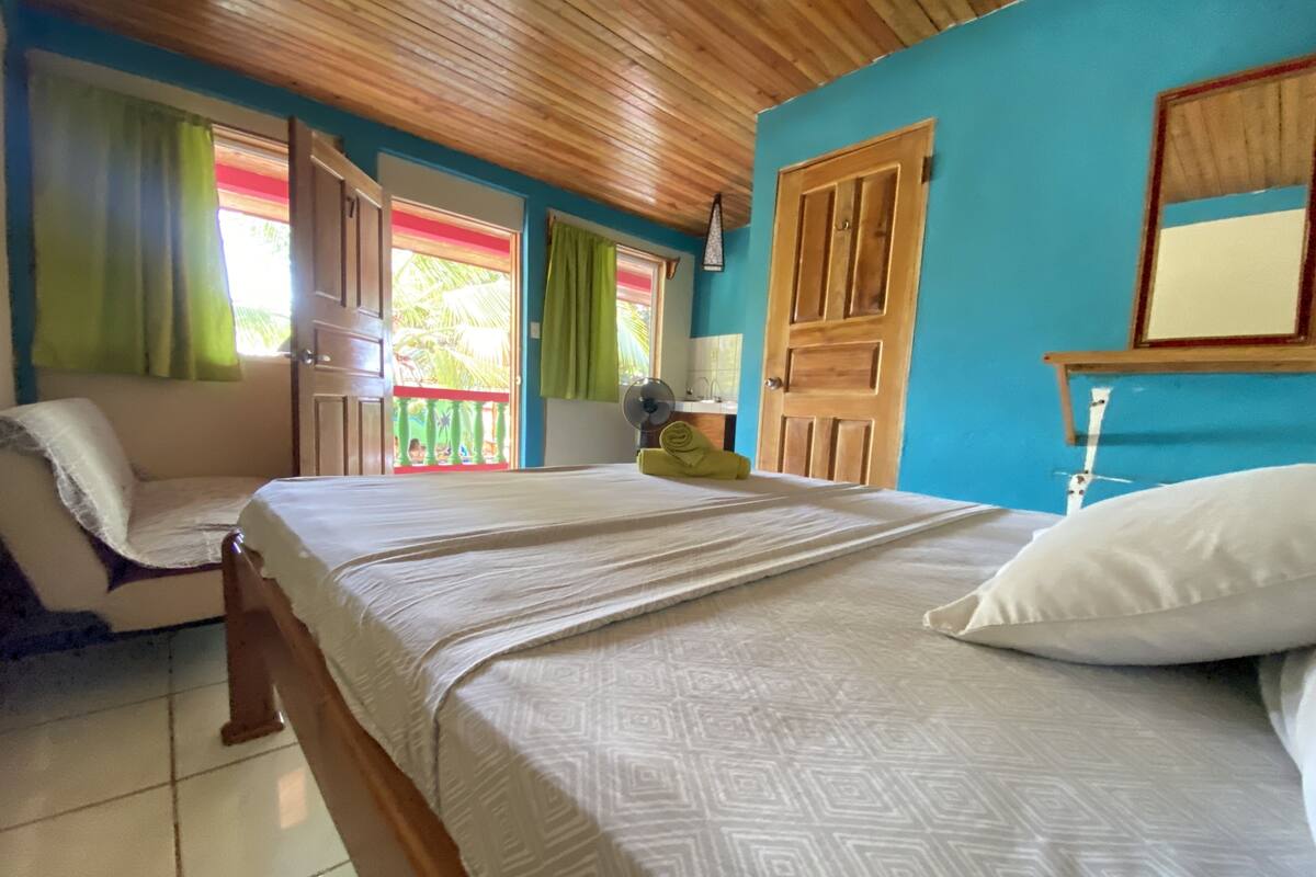 Une chambre à coucher avec un lit, un plafond en bois, une fenêtre avec des rideaux et une porte.