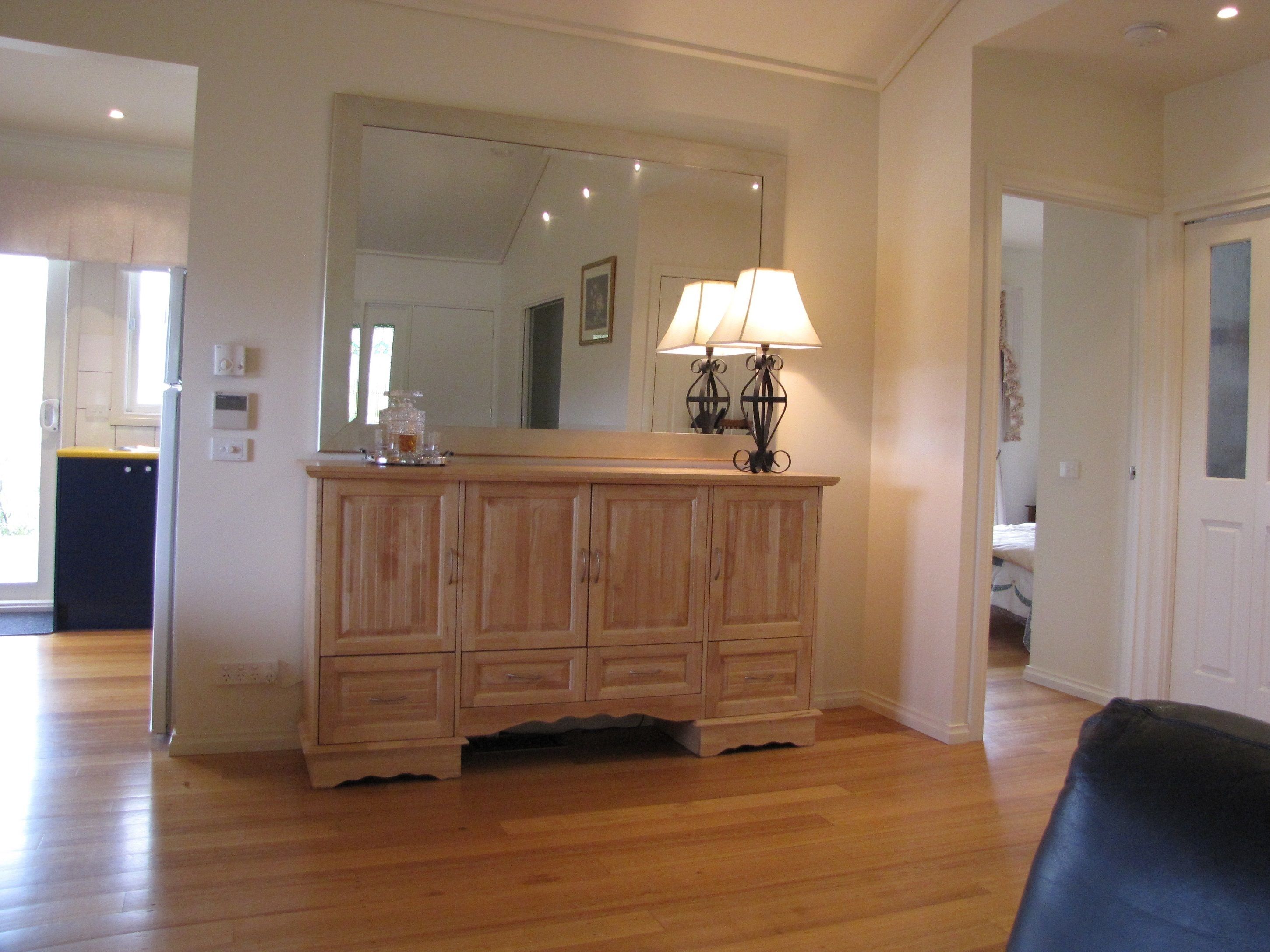 A wooden cabinet with a mirror above it, a lamp on top, and a small tray with items on the cabinet.