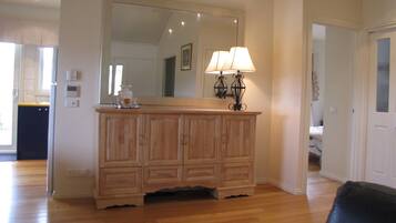 A wooden cabinet with a mirror above it, a lamp on top, and a small tray with items on the cabinet.