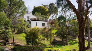 A white house with a balcony, surrounded by trees and a grassy yard. - Monigatti (Hepburn Springs)
