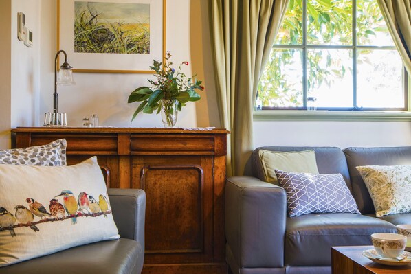 A cozy living room with a wooden cabinet, a vase with flowers, and a window with curtains.