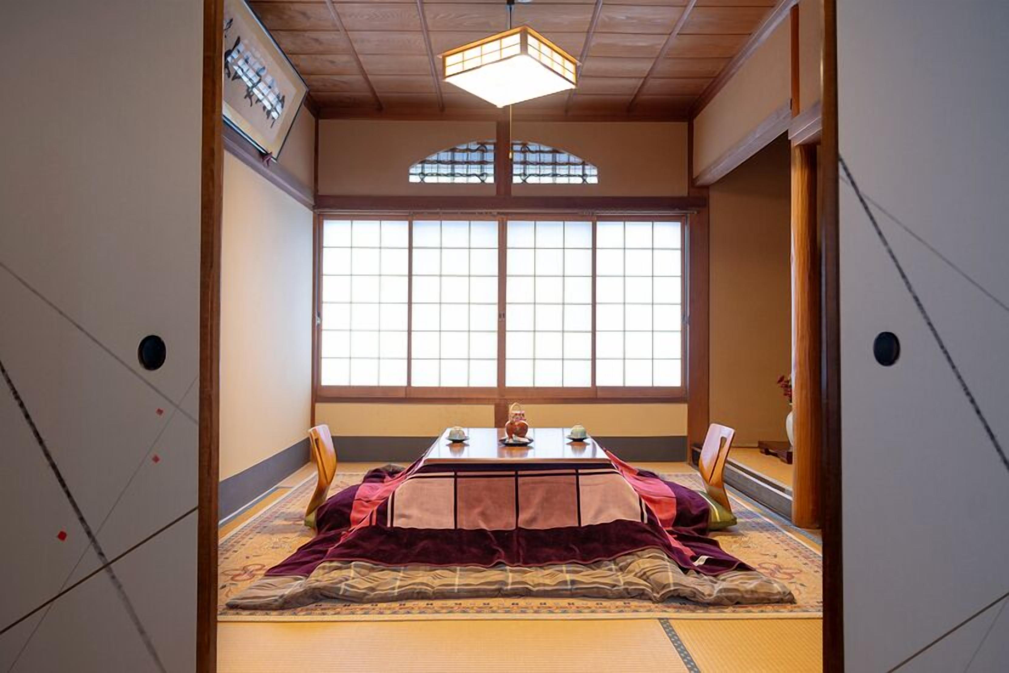 Um quarto japonês tradicional com tatames, uma mesa baixa com um conjunto de chá e uma janela grande.