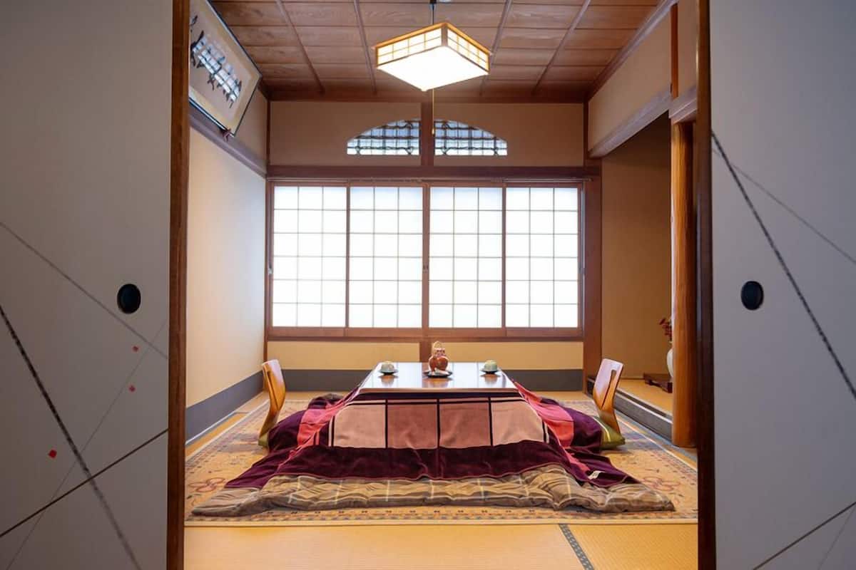 Una habitación tradicional japonesa con suelo de tatami, una mesa baja con un juego de té y un ventanal grande.
