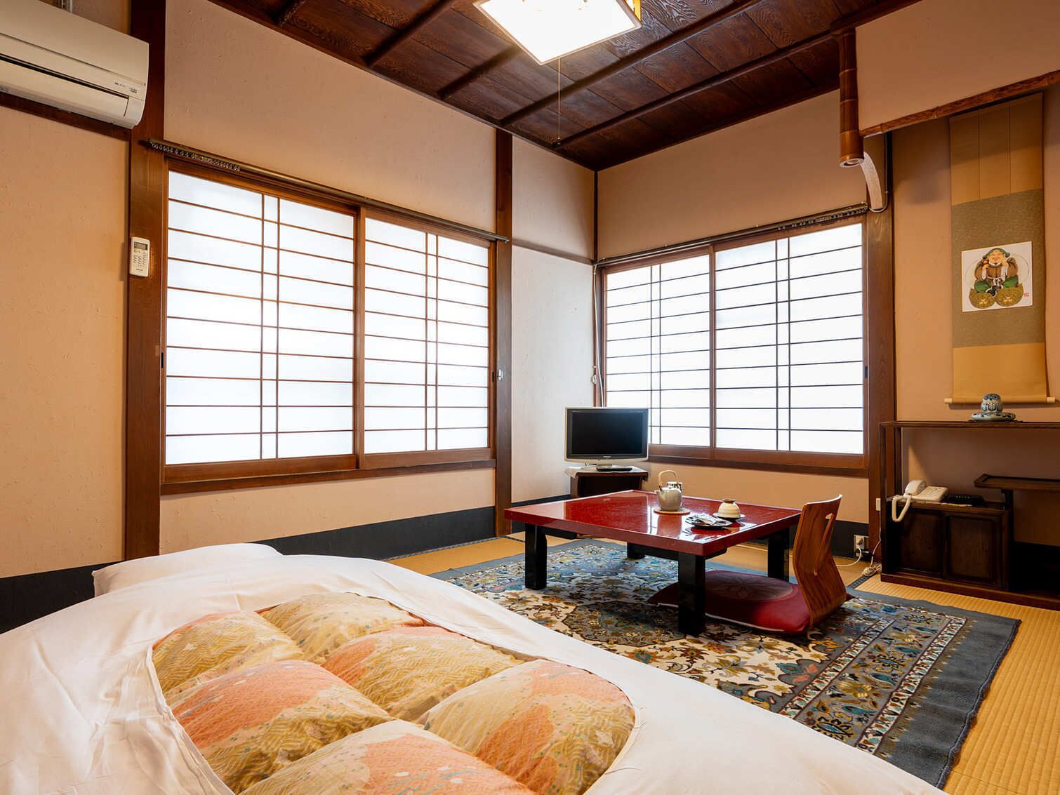 Um quarto japonês tradicional com tatames, um futon, uma televisão e uma pequena mesa com um bule de chá.