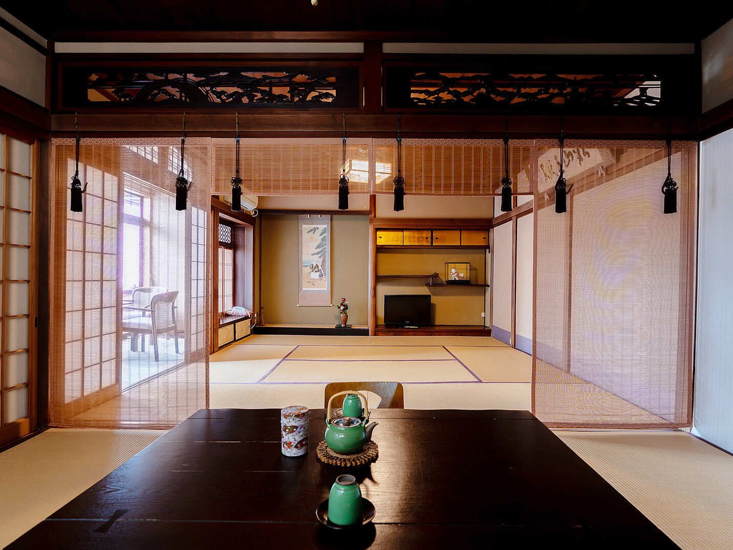 Um quarto japonês tradicional com piso de tatame, portas deslizantes e uma mesa baixa com jogos de chá verde.