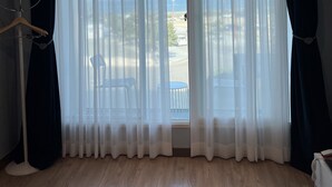 A room with a large window, wooden flooring, and a hanging coat rack. - Pinebeach Hotel Pohang (Pohang)