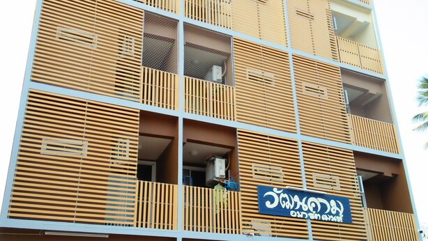 Un edificio moderno de varios pisos, con balcones de listones de madera y un cartel.