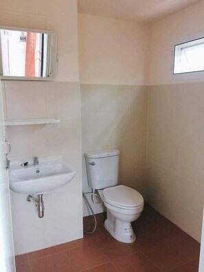 Une petite salle de bain avec un lavabo blanc, des toilettes et un miroir au-dessus du lavabo.