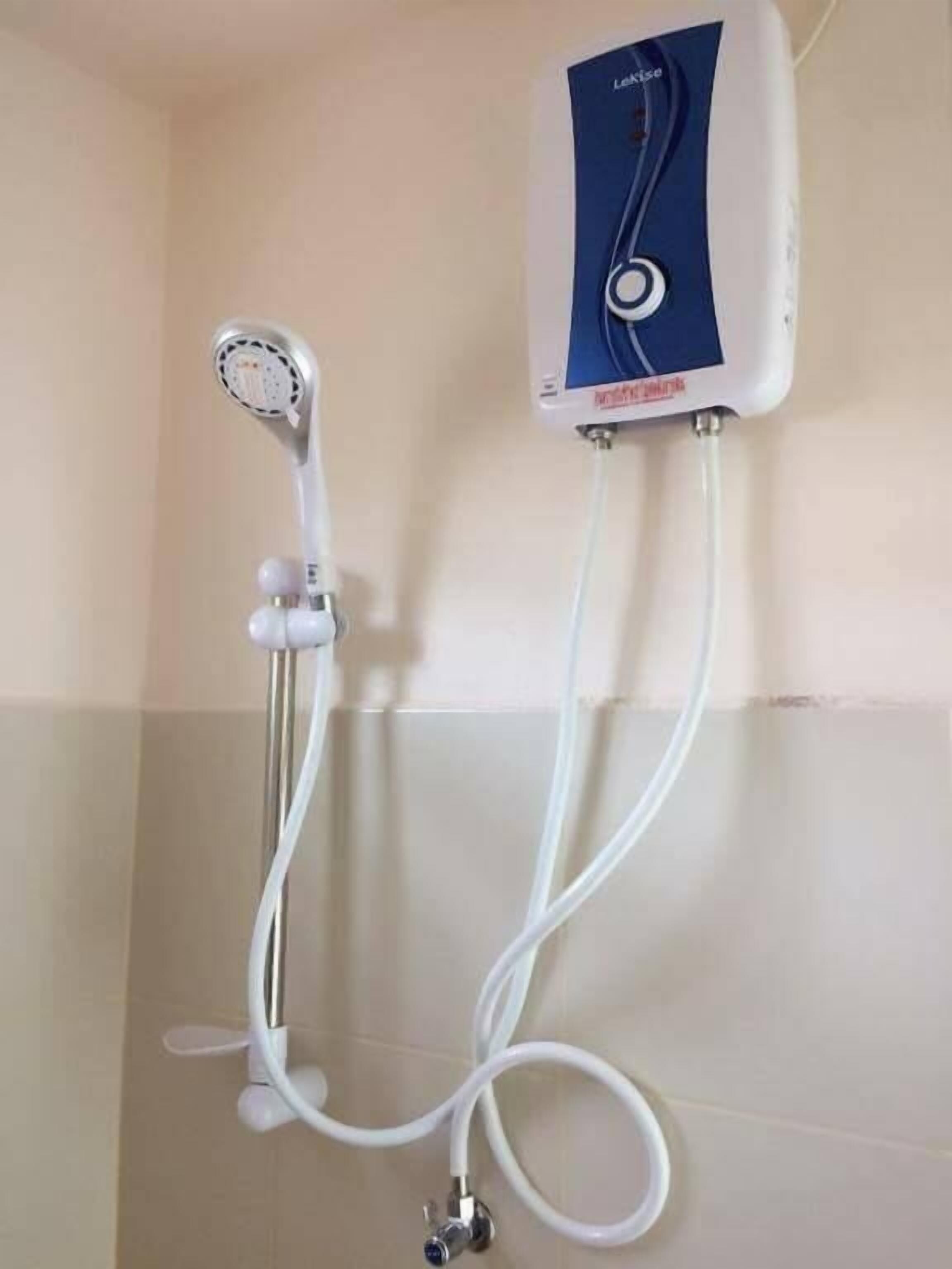 Een douche met een handdouche en een bedieningspaneel aan de muur.