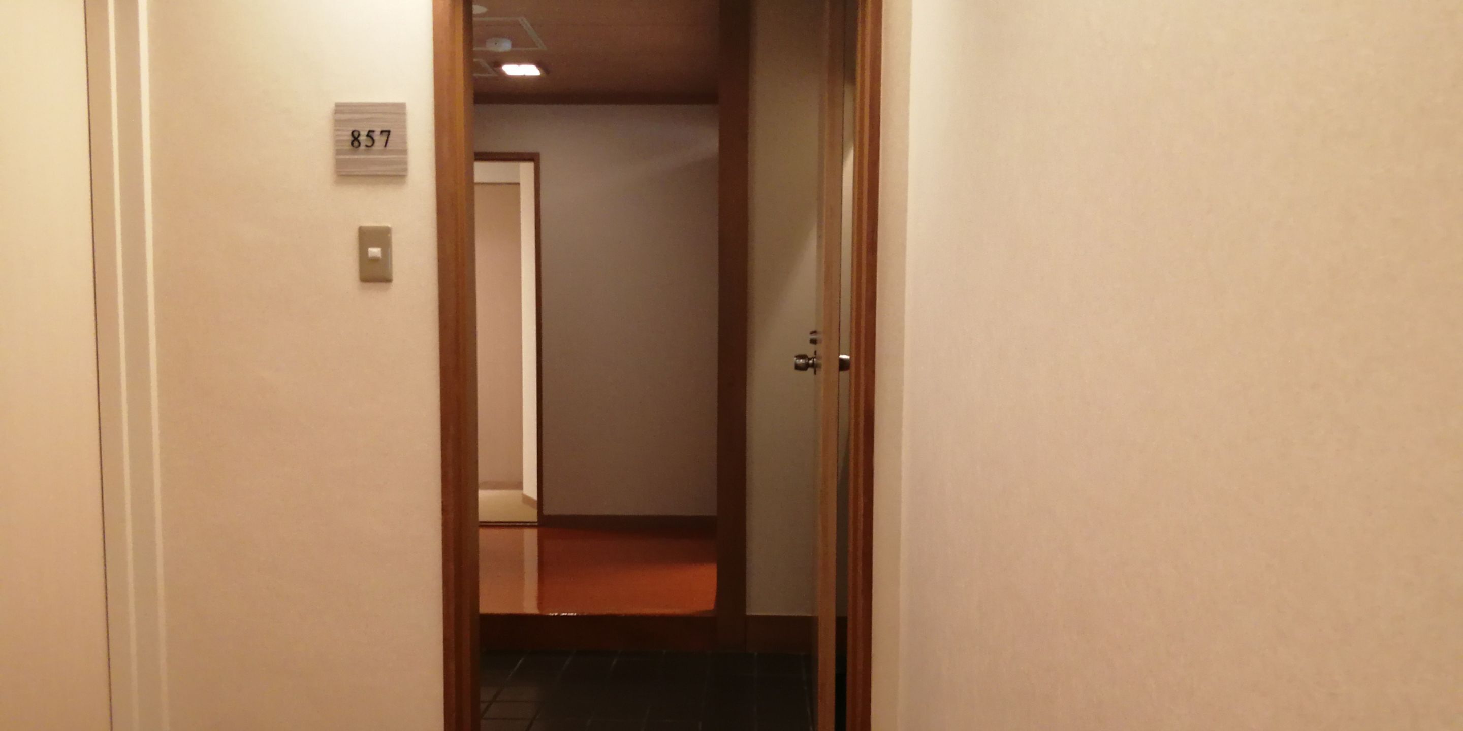 Un couloir étroit avec une porte portant le numéro « 857 » et un plancher en bois.