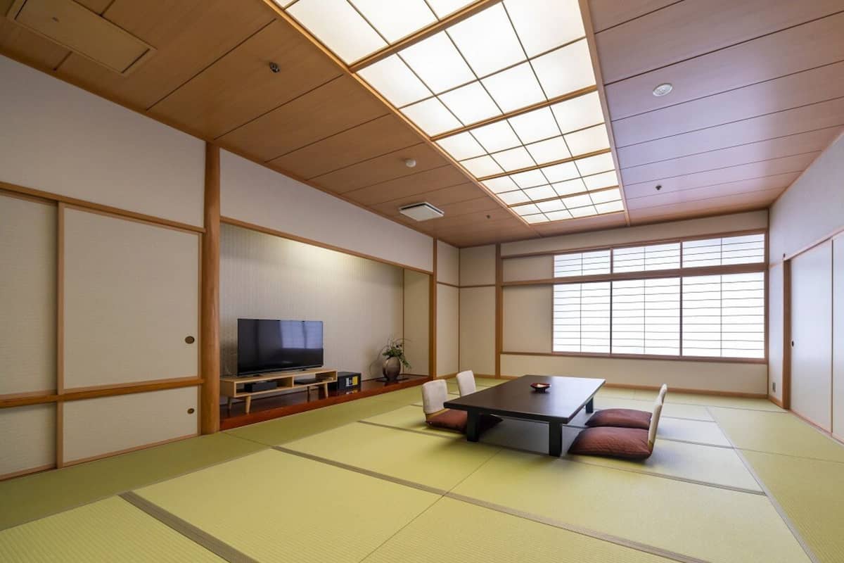 A tatami mat room with a television, a table, and a sofa.