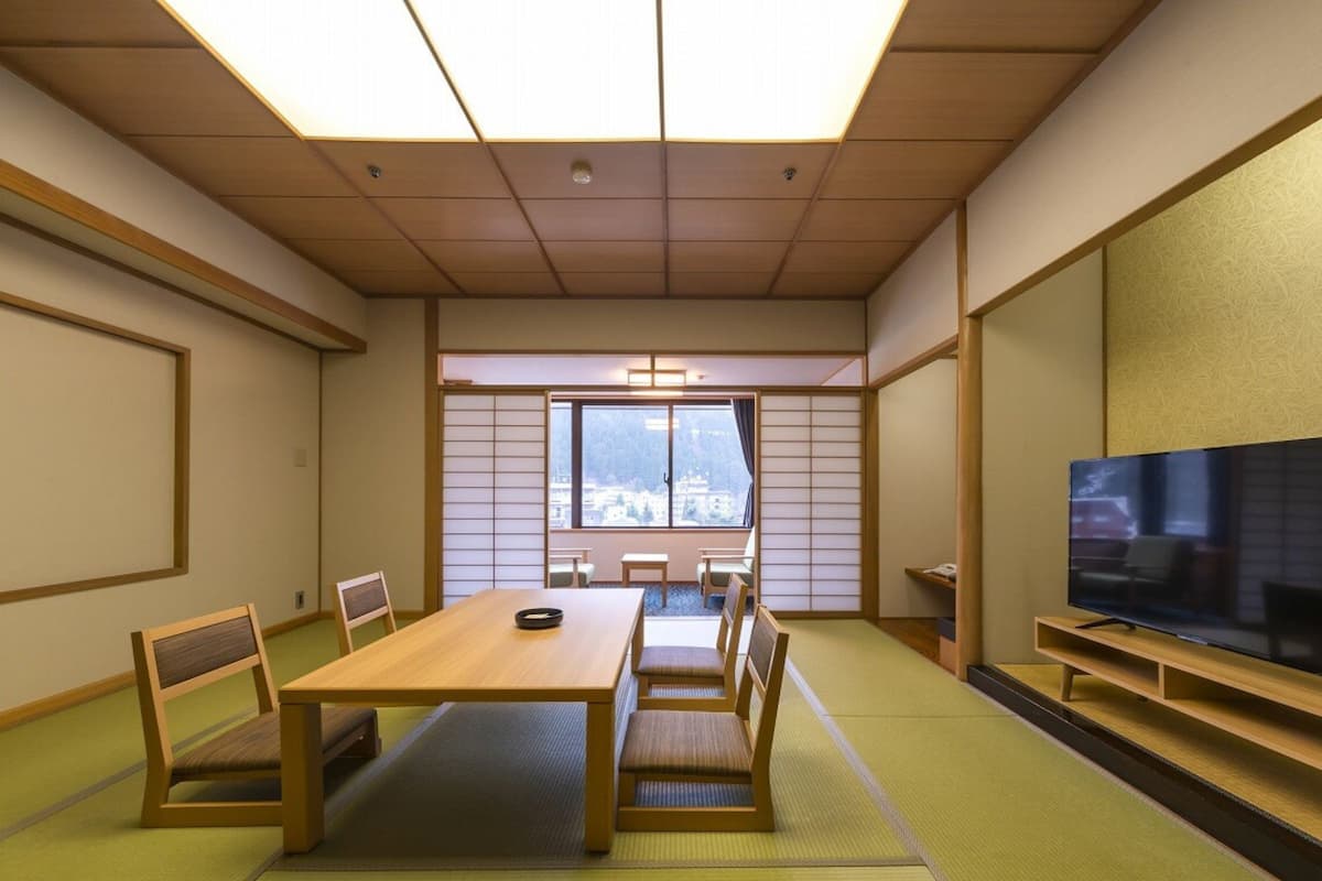 A traditional Japanese-style room with tatami flooring, a low table, and a television on a wooden stand.