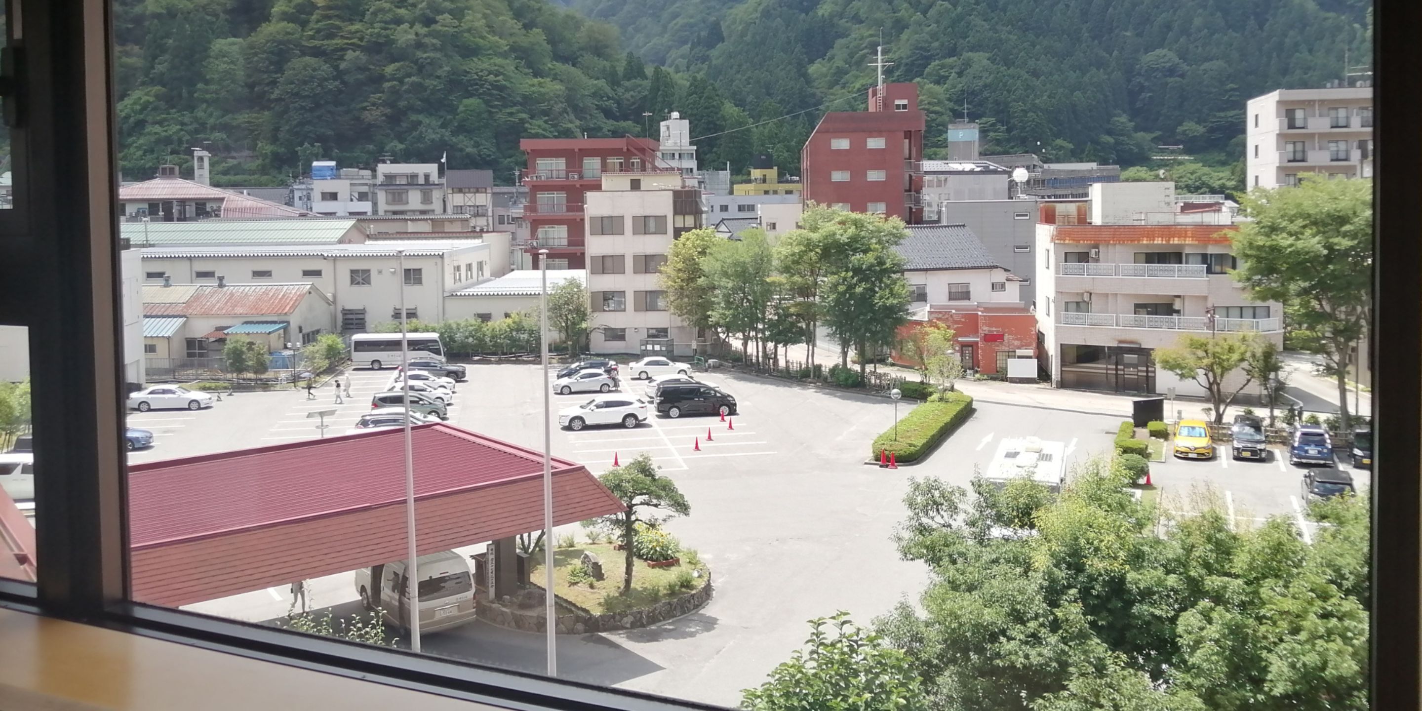 A parking lot with several cars and a building with a red roof in the foreground.