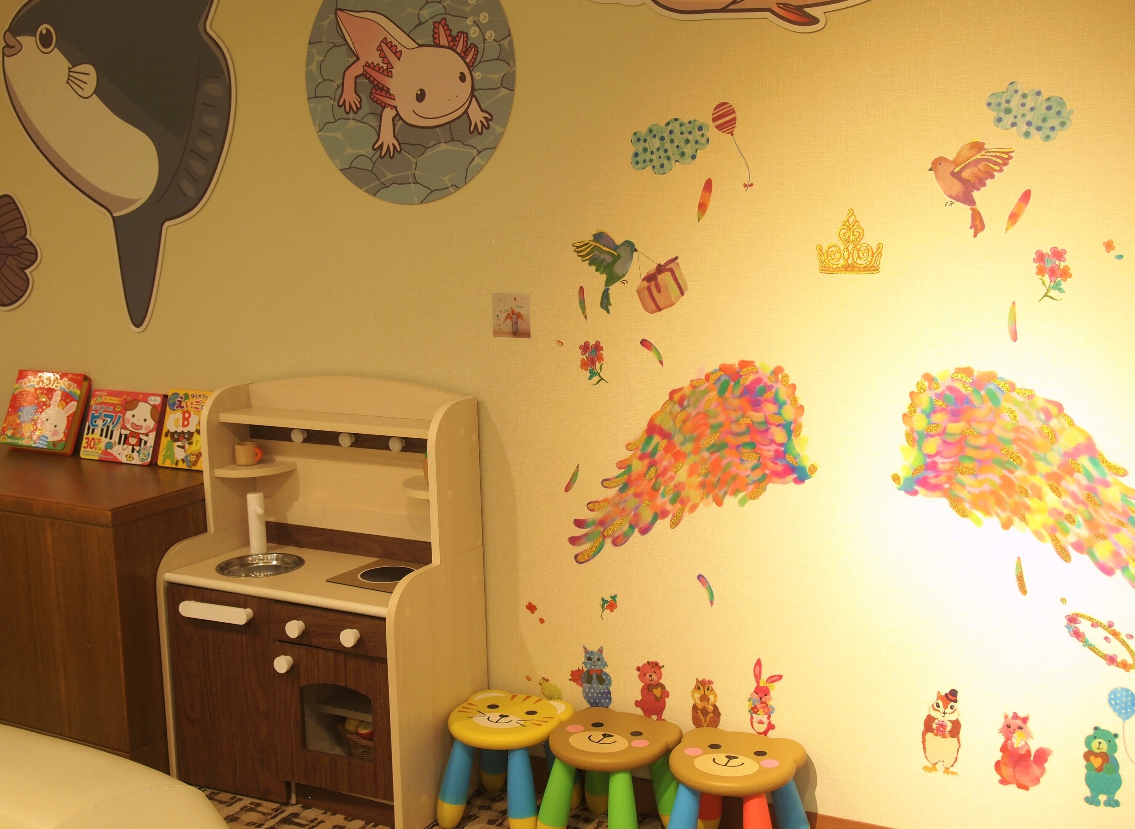 A child's play area with a small kitchen set, colorful wall decorations, and a sofa.