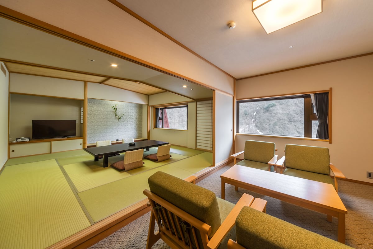 A tatami mat room with tatami mats, a low table, and wooden chairs.