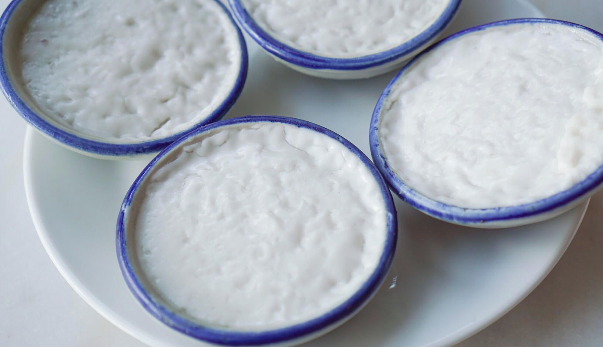 Cuatro recipientes con una sustancia blanca y cremosa sobre un plato.