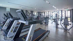 Un gimnasio moderno con cintas de correr, máquinas de pesas y un amplio ventanal con vistas a la ciudad.