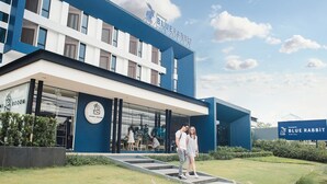 Un hotel moderno con fachada azul y blanca, una entrada visible y un letrero que dice 'Blue Rabbit Hotel'.