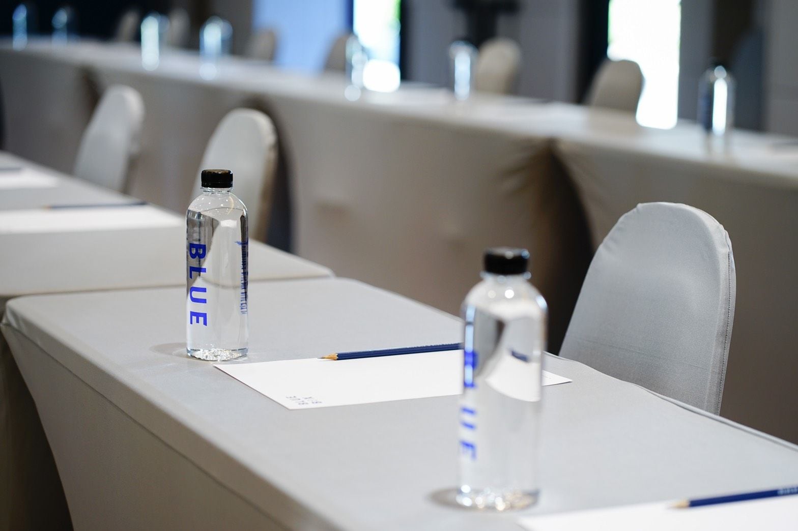 A conference table with water bottles labeled 'BLUE' and a notepad.