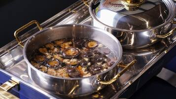 A stainless steel stove with two pots containing food.