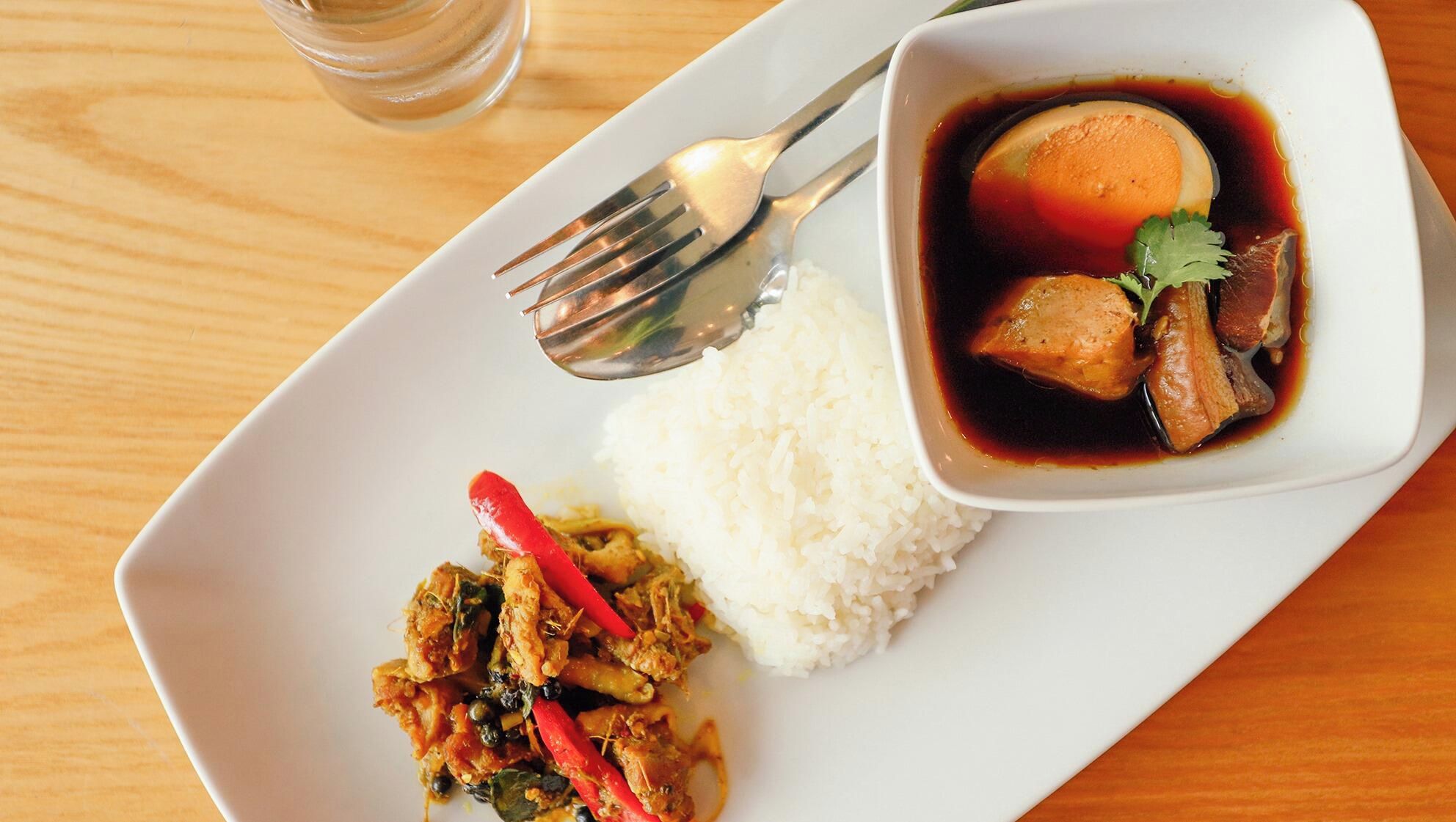 A plate with white rice, a bowl of soup with meat and vegetables, and a side dish of stir-fried chicken with red peppers.
