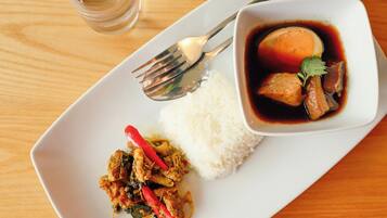 A plate with white rice, a bowl of soup with meat and vegetables, and a side dish of stir-fried chicken with red peppers.
