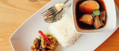 A plate with white rice, a bowl of soup with meat and vegetables, and a side dish of stir-fried chicken with red peppers.