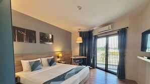 Habitación de hotel con una cama grande, un escritorio, una silla, un televisor y vistas al exterior por la ventana.