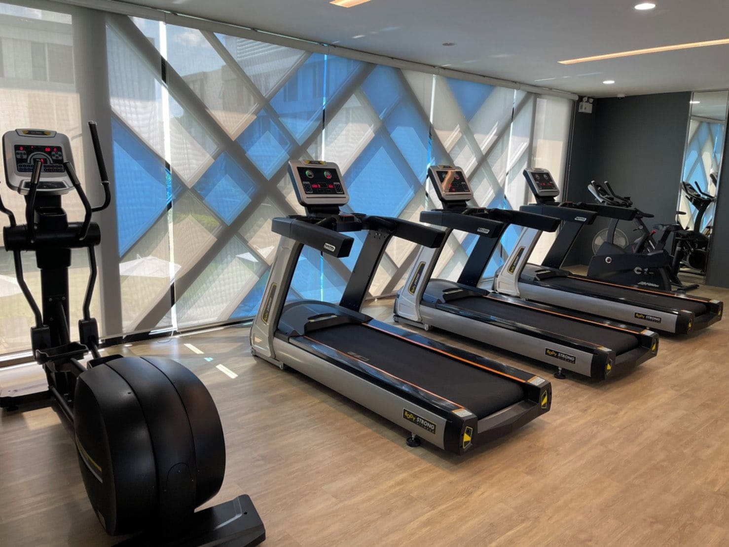 Un gimnasio con cintas de correr, elípticas y una bicicleta estática.