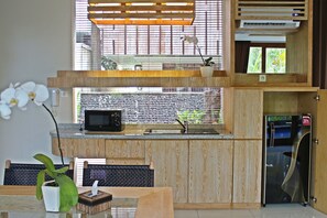 A modern kitchen with a built-in microwave, a sink, and a window with a view of greenery. - Greenfield Luxury Villas (Ubud)