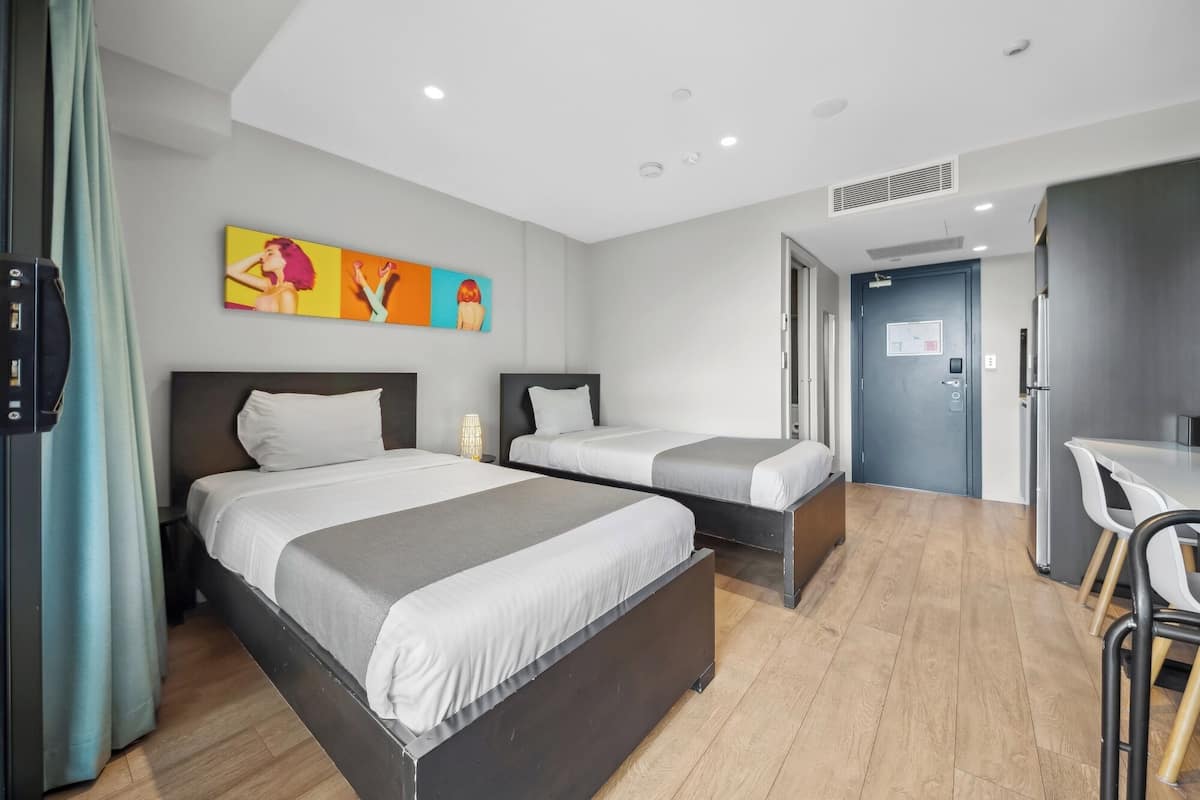 A hotel room with two beds, a desk, and a chair.