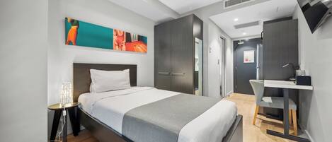 Una habitación de hotel moderna con una cama grande, un escritorio y una televisión.