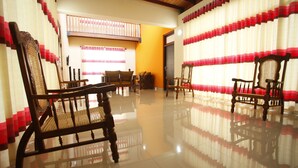 A spacious room with a polished floor, wooden chairs, and a sofa. - APL Apartments (Peliyagoda)