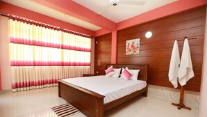 A bedroom with a wooden bed, a nightstand, a wall-mounted towel rack, and a window with curtains. - APL Apartments (Peliyagoda)