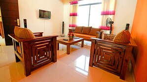 A living room with a sofa, two armchairs, a coffee table, a TV, and a window with curtains. - APL Apartments (Peliyagoda)