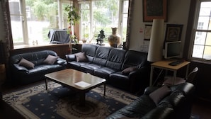 A living room with a black leather sofa set, a coffee table, and a patterned rug. - Australia House (Kutchan)