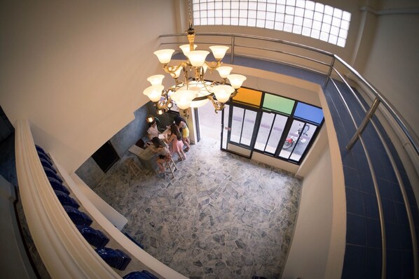 A staircase with a chandelier and a view of the street through a window. - Laluna River House (Chanthaburi)