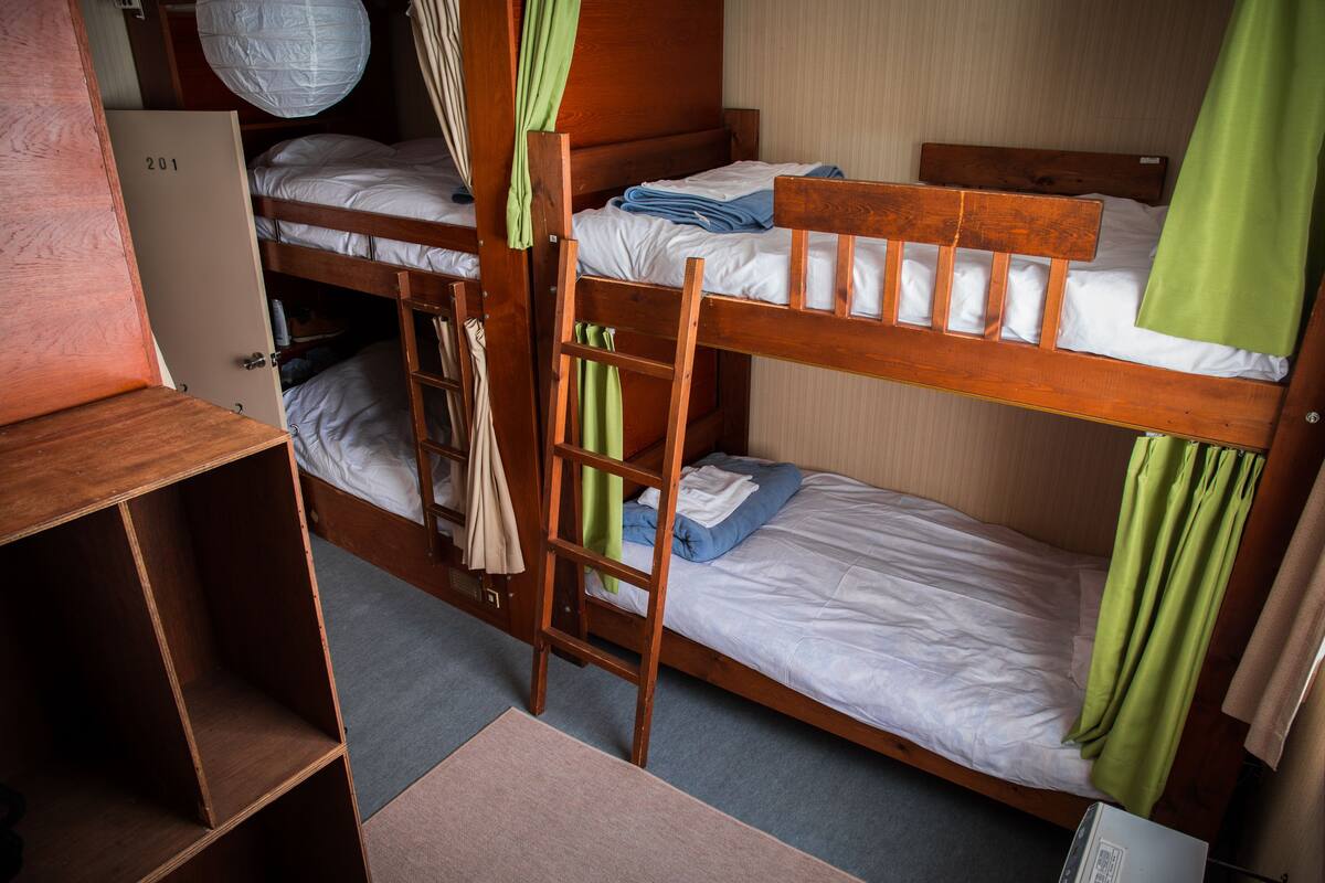 Habitación con literas, un armario y un escritorio pequeño.
