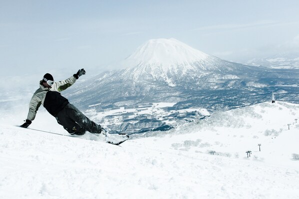 A snowboarder on a snowy slope with a mountain in the background.