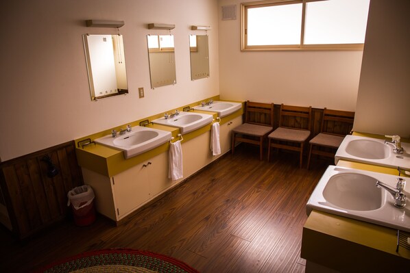 A bathroom with two sinks, mirrors, wooden chairs, and a window. - Annupuri Oasis Lodge (Niseko)
