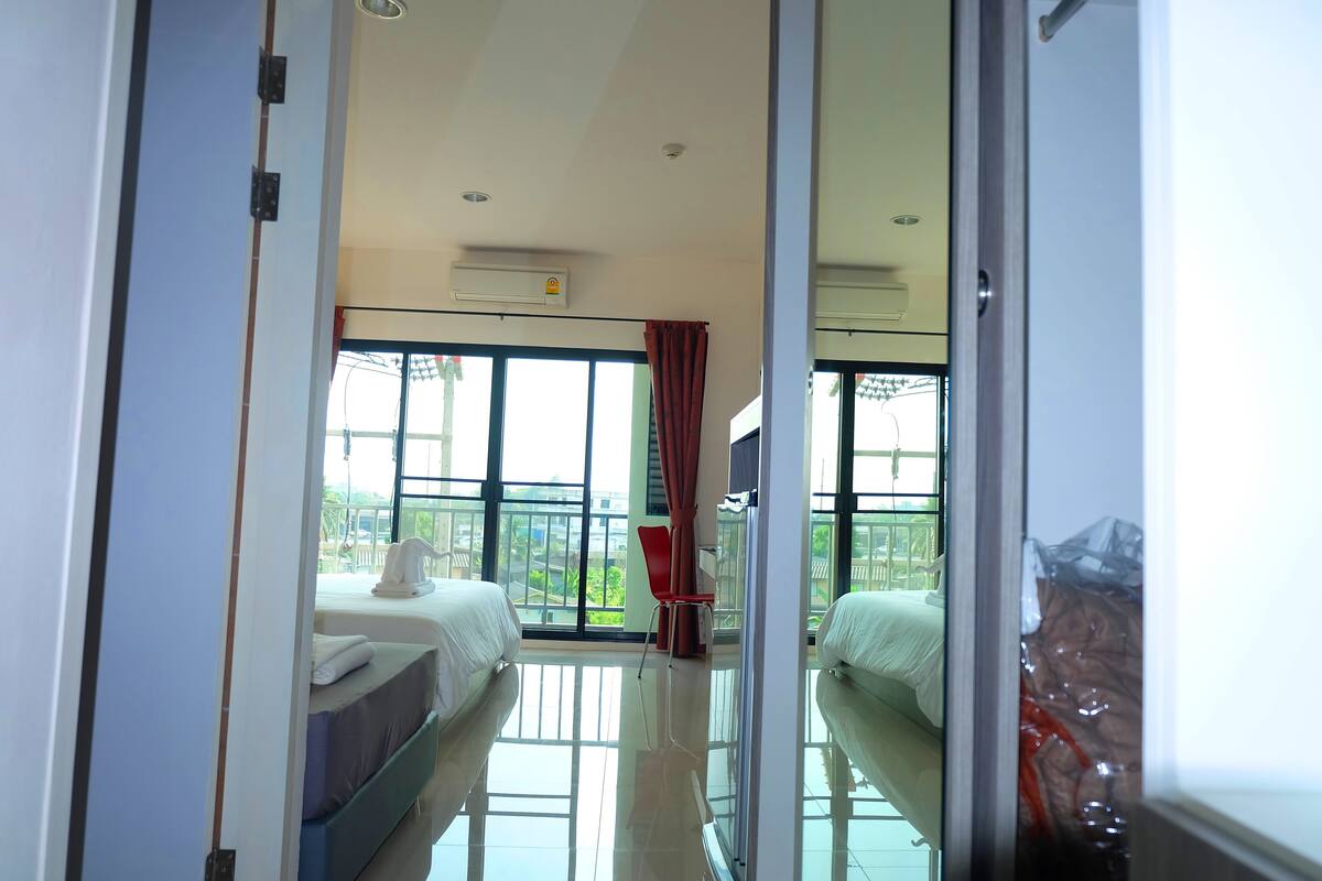 A hotel room with two beds, a balcony with a view, and a red chair.