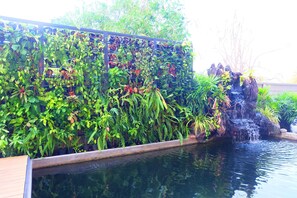 A garden with a water feature and a variety of plants. - The Pride (Sam Phran)