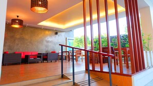 A modern interior with a staircase, red seating, and hanging lights. - The Pride (Sam Phran)