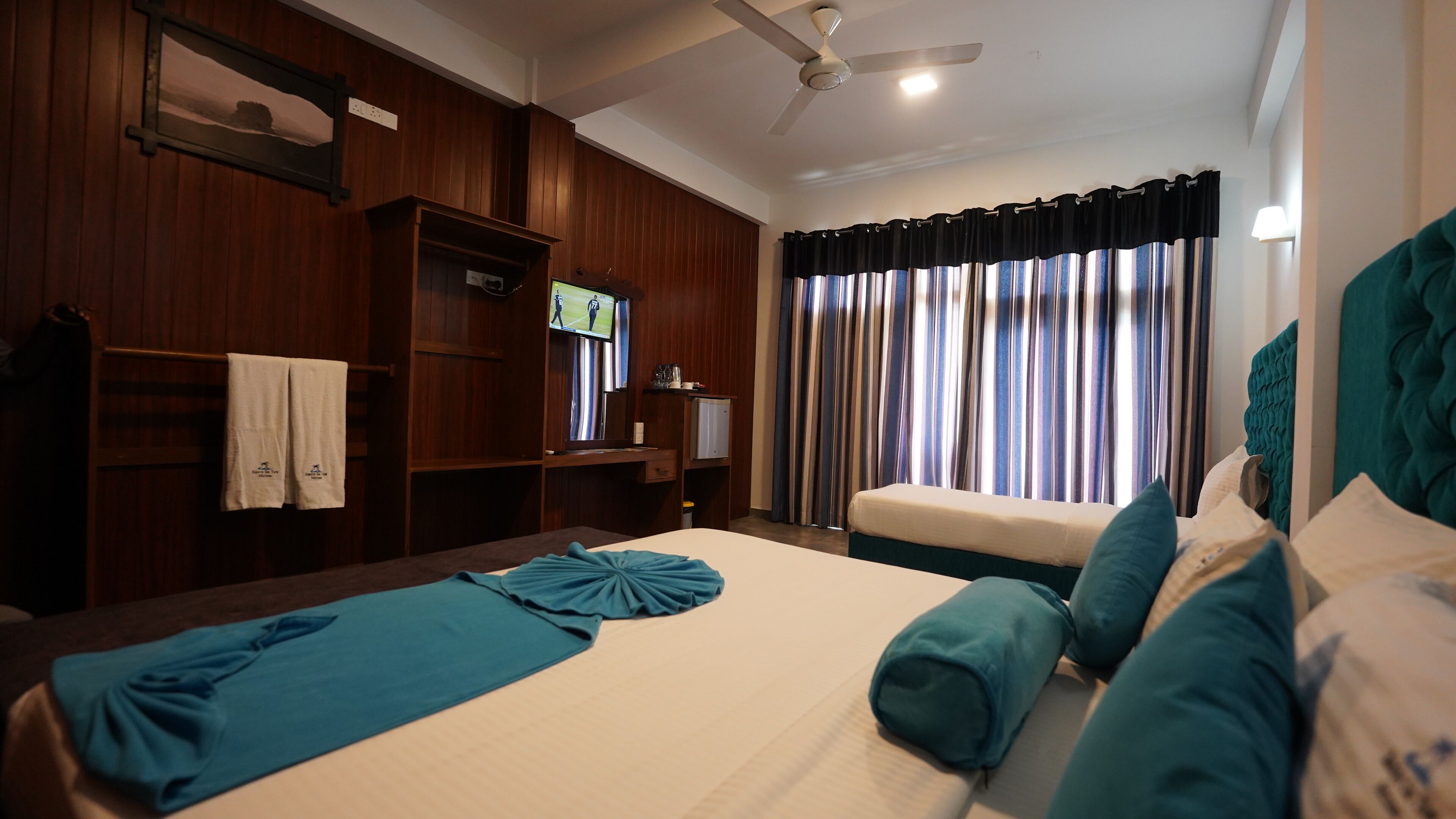 A hotel room with a bed, a desk, a television, and a window with curtains.