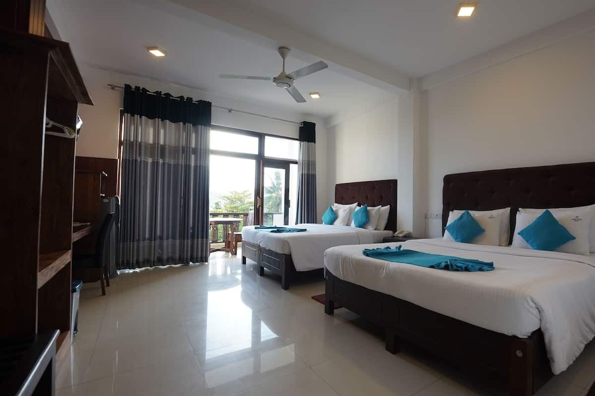 A hotel room with two beds, a ceiling fan, and a balcony with curtains.