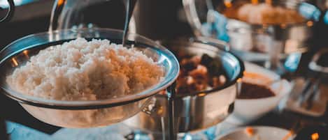 Un buffet proposant une variété de plats, notamment du riz, des légumes et d’autres aliments préparés.